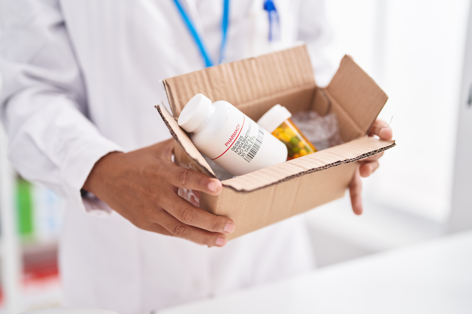 pharmacist packing box of prescription medications for delivery