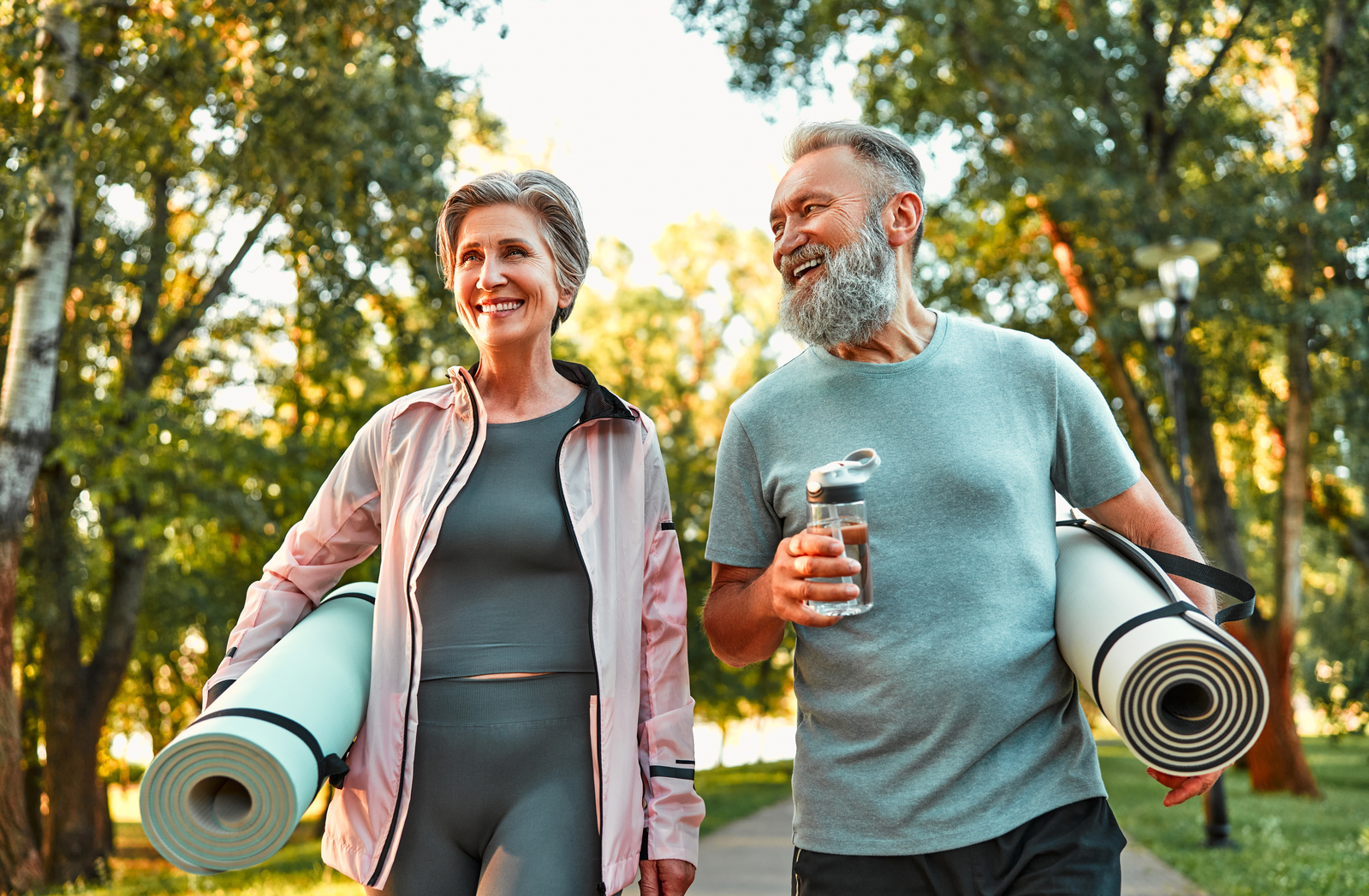 senior couple carrying yoga mats for outdoor workout