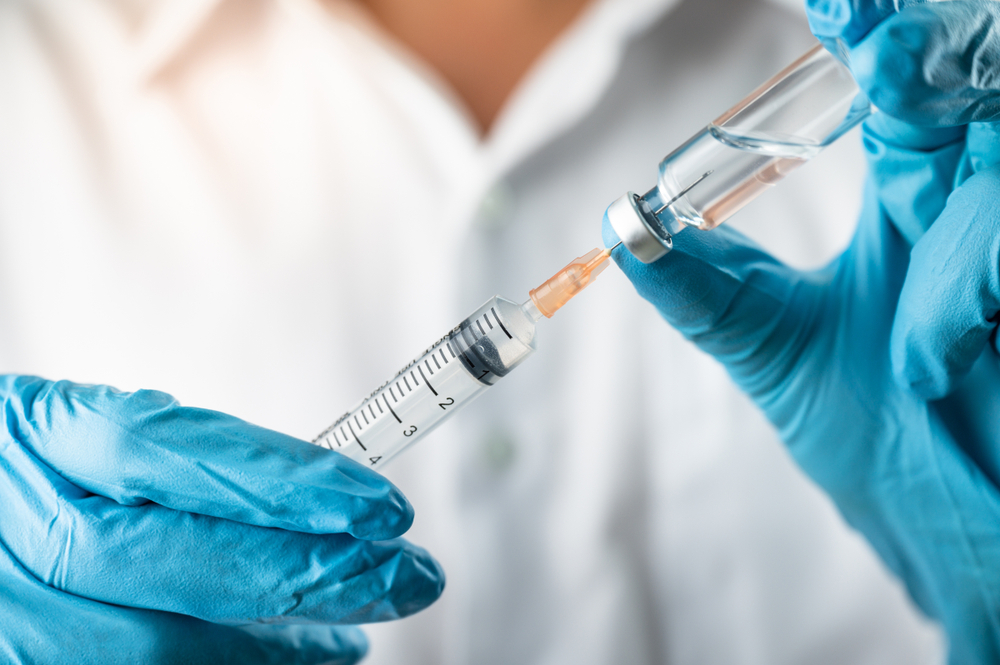 gloved hands filling syringe with vaccine