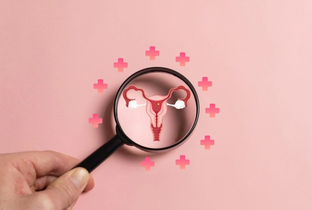 hand holding magnifying glass over diagram of uterus to represent women's health