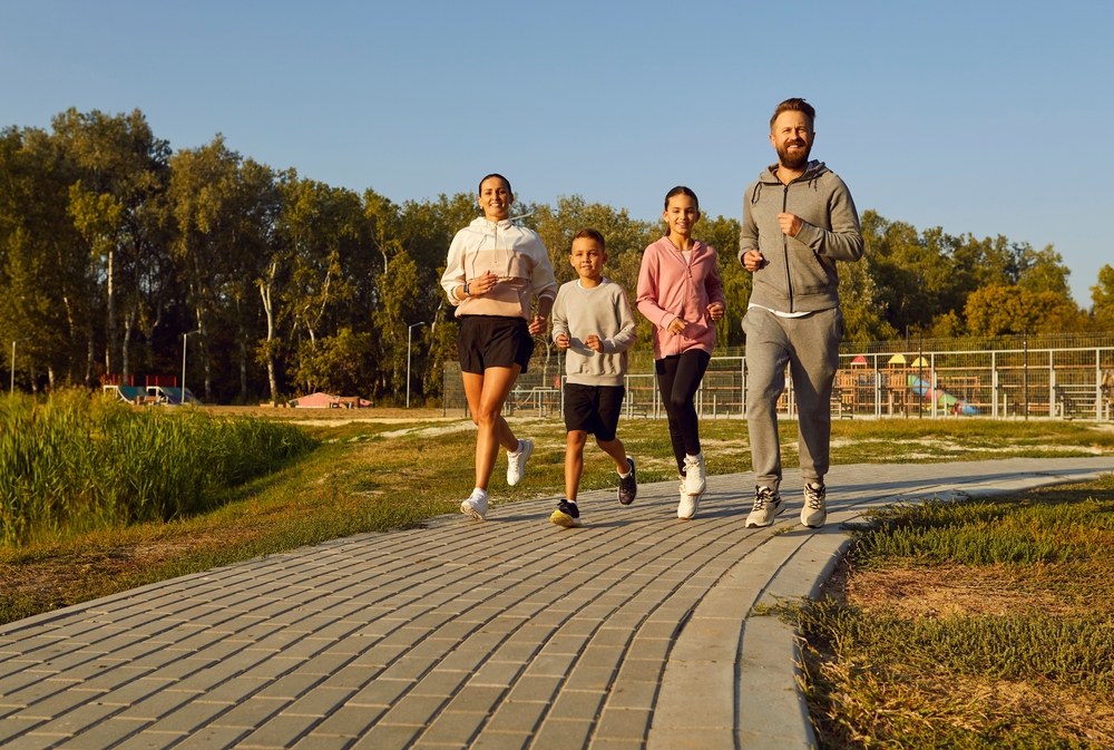 two parents and two kids running outdoors