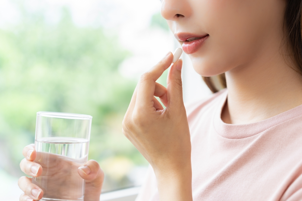 woman taking pill with glass of water