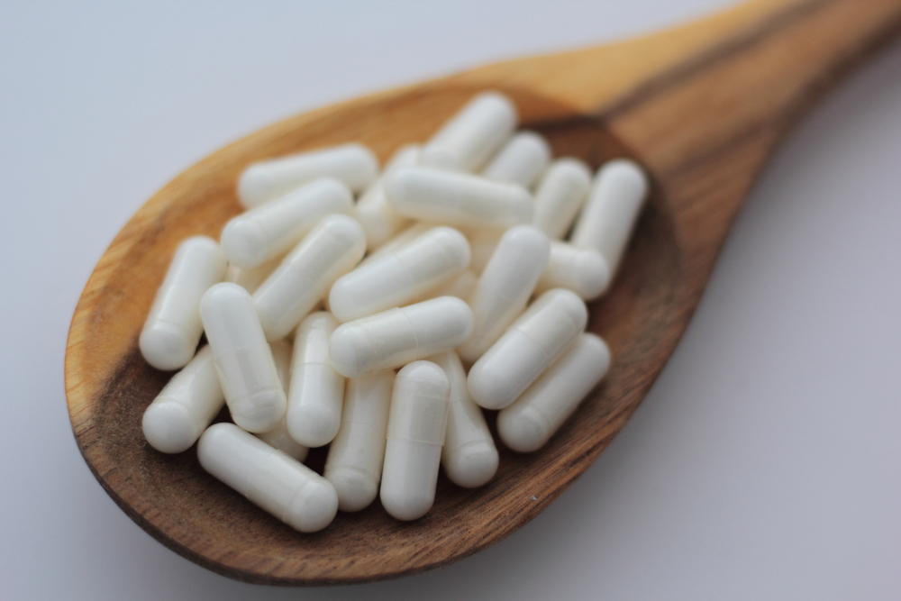 inositol capsules on wooden spoon